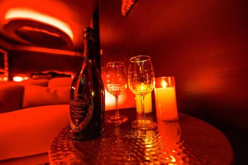 una mesa con dos vasos y una botella y una vela en LOVE ROOM TOULOUSE - Centre, en Toulouse