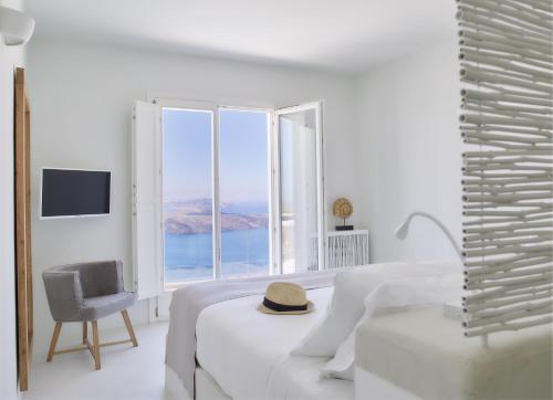 a white room with a bed and a chair and a window at Nafsika Estate in Megalokhori