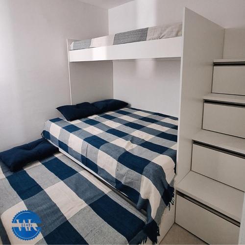 a bedroom with a bunk bed with a blue and white checkered blanket at WK Flat em Porto de Galinhas in Porto De Galinhas