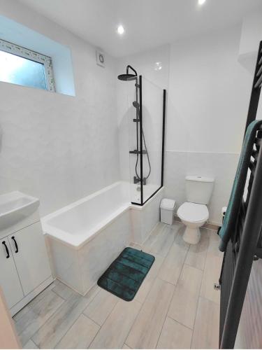 a white bathroom with a tub and a toilet at Blue Door Apartments in Dover