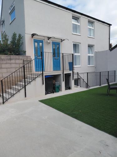 a white house with blue doors and a lawn at Blue Door Apartments in Dover