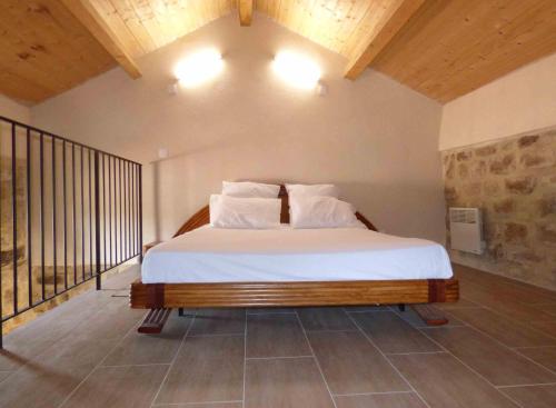 une chambre avec un lit avec des draps blancs et des oreillers dans l'établissement Hameau de Gratte, à Faugères