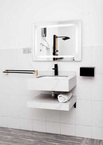 ein weißes Badezimmer mit Waschbecken und Spiegel in der Unterkunft Sleepeaze Hotel in Afienya