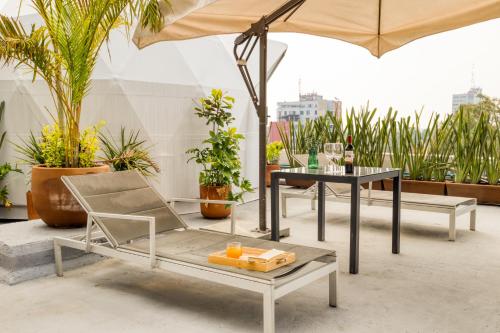 Un patio con una mesa y sillas y una sombrilla. en Casa Umbral Glampings, en Ciudad de México