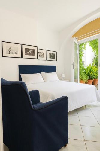 Un dormitorio con una cama blanca y una silla azul. en CAPRI DESIGN ROOM, en Capri
