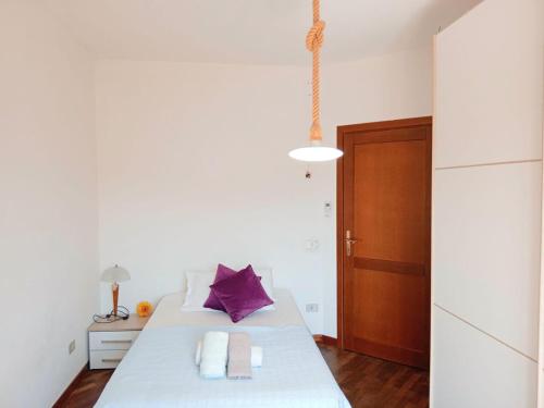 a bedroom with a large white bed with purple pillows at casa mare bellissima in Alghero