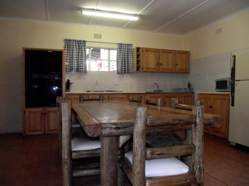 a kitchen with a wooden table and a refrigerator at Jock-Sabie Lodge in Sabie