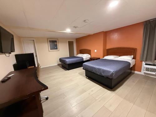 a hotel room with two beds and a flat screen tv at Travelers Motor Lodge in North Smithfield