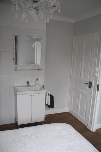a white bathroom with a sink and a mirror at Apartment Fleur de Lys Bleue in Soudaine-Lavinadière