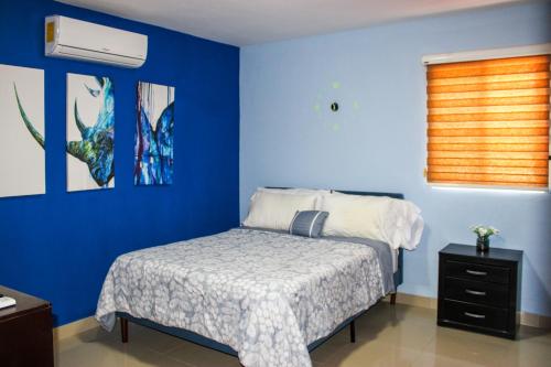 ein Schlafzimmer mit einem Bett und einer blauen Wand in der Unterkunft Terry's House in Cozumel