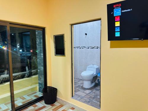 a bathroom with a toilet and a tv on the wall at Hospedaje chachalacas in Chachalacas