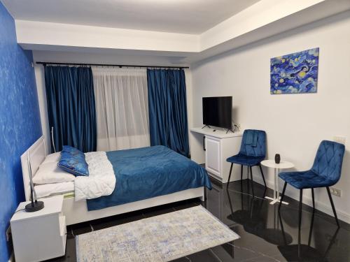 a bedroom with a bed and two blue chairs at DAR House in Vîlcele