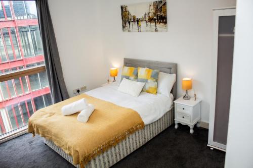 a bedroom with a bed with yellow and white pillows at Modern 2 Bed City Center Apartment in Manchester