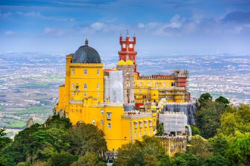 un edificio amarillo en la cima de una montaña en Totally Tour Portugal LDA, en Lisboa