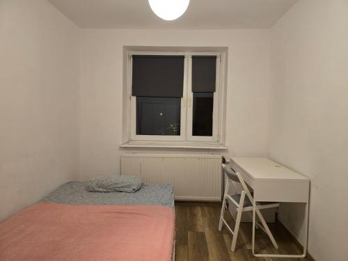 a bedroom with a bed and a desk and a window at Home 24 check-in in Poznań