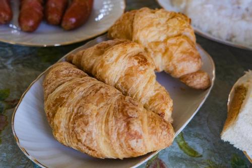 zwei Teller mit Croissants und anderen Speisen auf einem Tisch in der Unterkunft Elegance Cottage in Nikawatawana
