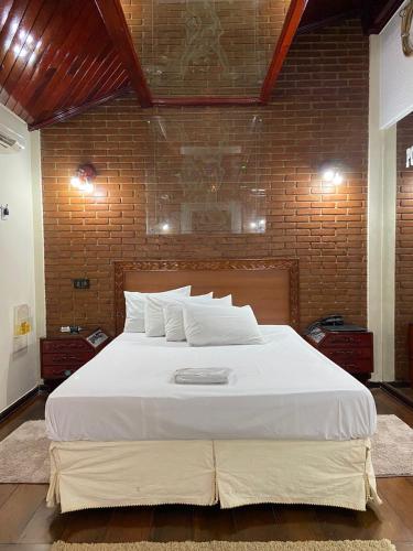 a large white bed in a room with a brick wall at Motel Pousada do Cowboy in Sao Paulo