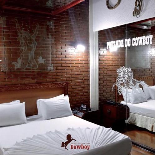 a bedroom with two beds and a brick wall at Motel Pousada do Cowboy in Sao Paulo