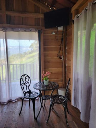 a table and chairs on a porch with a window at Cabaña Doña Flor in Turrialba