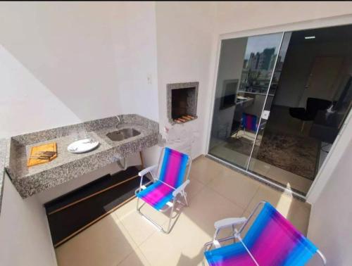 two blue and pink chairs in a room with a counter at Apê da Thais in Balneário Camboriú