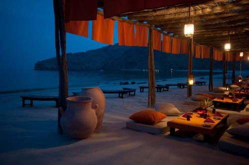 a restaurant on the beach with tables and chairs at Six Senses Zighy Bay in Dibba