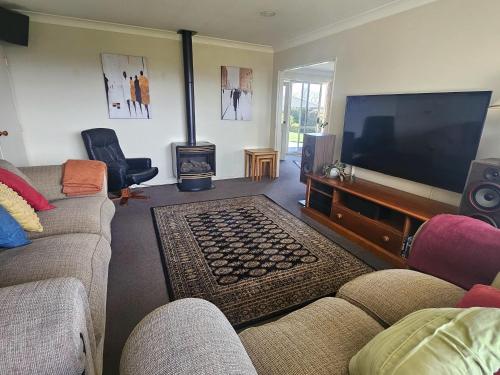 a living room with a large flat screen tv at The Holiday Haven in Tauranga