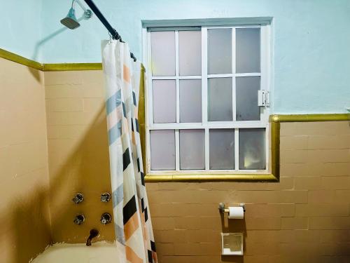a bathroom with a window and a shower curtain at La Casita in Mexico City