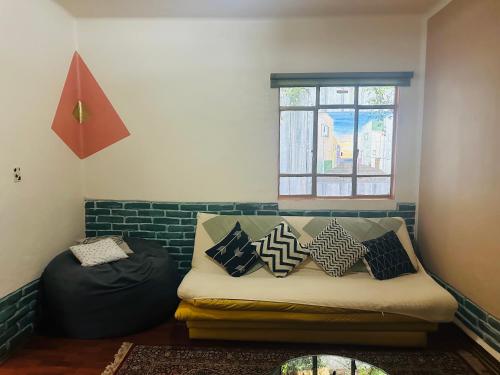 a room with a couch with pillows and a window at La Casita in Mexico City