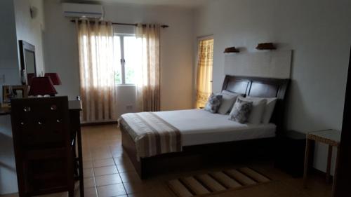a bedroom with a bed and a dresser and a window at Villa Kayola - Self Catering in Mahe