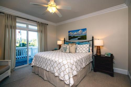 a bedroom with a bed with a ceiling fan and a balcony at I'll Have Another in Edisto Island