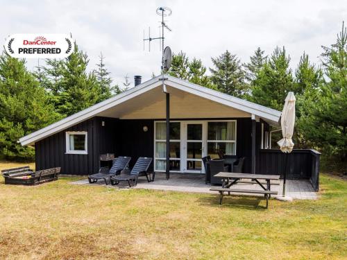 a black cabin with a picnic table and benches at Enchanting Hideaway in Henne Town-By Traum in Henne Strand