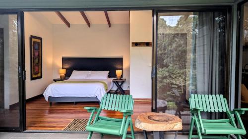 - une chambre avec un lit et deux chaises vertes dans l'établissement Olingo Monteverde - Studio Apartment with Jacuzzi, à Monteverde Costa Rica
