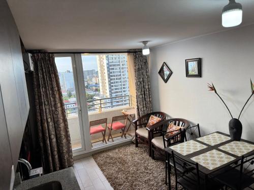 ein Wohnzimmer mit einem Tisch und Stühlen sowie einem großen Fenster in der Unterkunft Concep Centro Freiré-Tucapel in Concepción