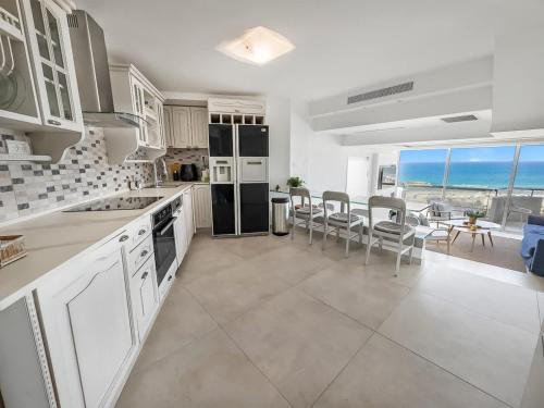 una cocina con electrodomésticos negros, mesa y sillas en Blue Horizon Penthouse, en Herzliya Pituah