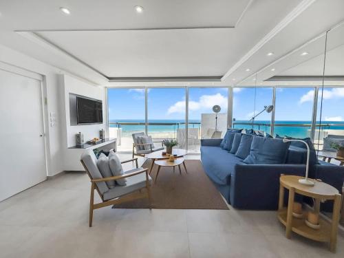 a living room with a blue couch and a view of the ocean at Blue Horizon Penthouse in Herzliya B
