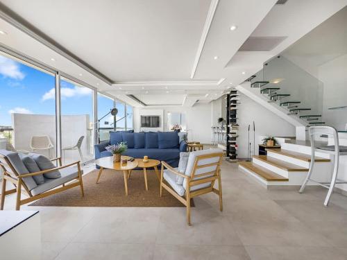 a living room with a blue couch and chairs at Blue Horizon Penthouse in Herzliya B