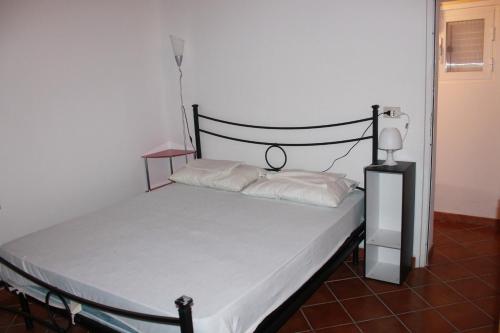 a bed with white sheets and a black headboard in a room at La Piccola Musa in Fontane Bianche