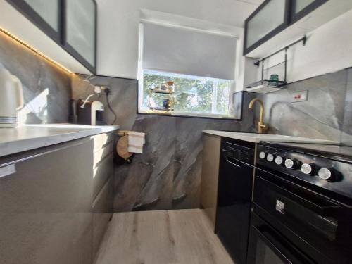 a small kitchen with a sink and a stove at Home on the Broads Just Renovated in Lowestoft