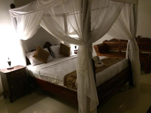 a bedroom with a canopy bed with white curtains at Betutu Bali Villas in Ubud