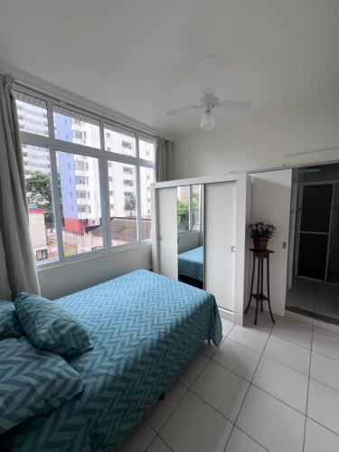 a bedroom with a bed and a large window at Apartamento 2 suítes Pitangueiras Guarujá in Guarujá