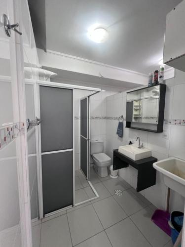 a white bathroom with a sink and a toilet at Apartamento 2 suítes Pitangueiras Guarujá in Guarujá