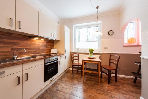 a kitchen with white cabinets and a table with chairs at Hotel Fauna in Breiholz