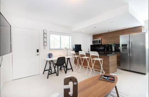 a kitchen with a table and a stainless steel refrigerator at GroveO6 10 minutes from the Beach in Miami