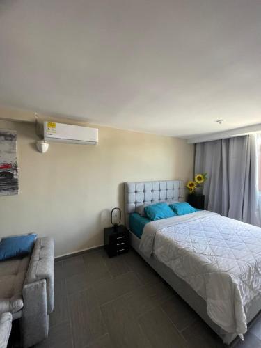 a bedroom with a large bed and a couch at Moderno Apto con Aire Acondicionado Vista a Ruitoque cerca a FOSCAL in Floridablanca
