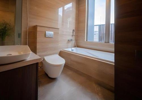 a bathroom with a toilet and a tub and a sink at Arvesto Jakarta in Jakarta