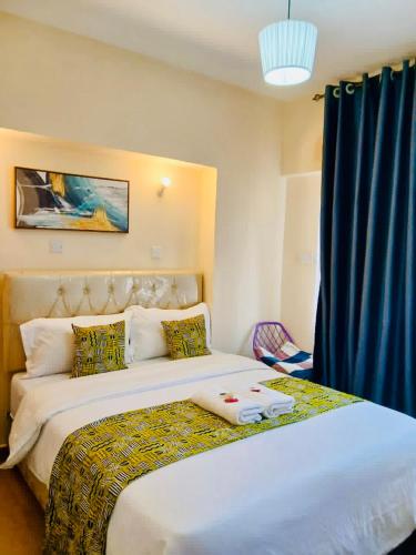 a bedroom with a large white bed with a blue curtain at Crystal Sky 2-Bedrooms with 3 beds Pool and balcony in Nairobi