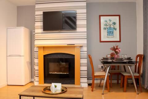 a living room with a table and a fireplace with a tv at Entire 3 Bedroom Home Rotherham in Rawmarsh