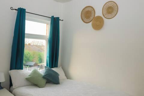 a room with a window and a bed with blue curtains at Entire 3 Bedroom Home Rotherham in Rawmarsh
