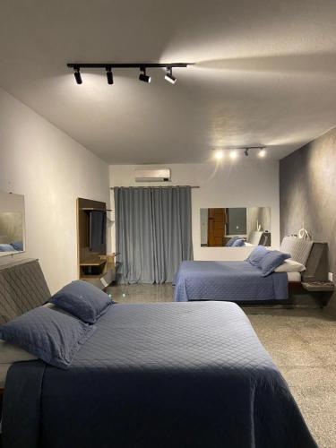 a hotel room with two beds and a television at Gran Luha Motel, Hotel in Brotas