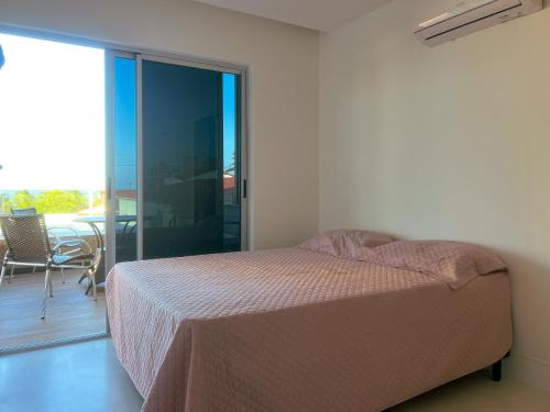 ein Schlafzimmer mit einem Bett und einem Balkon in der Unterkunft Casa de Verão - Praia de Muriú in Muriú